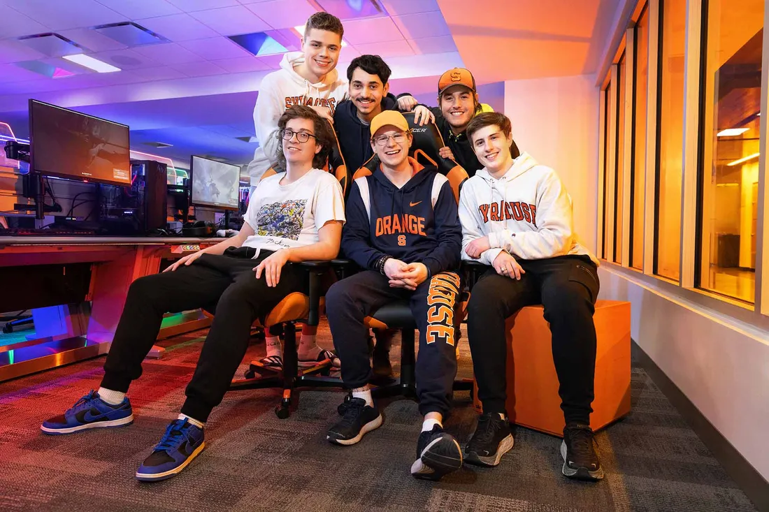 Group of students sits together posing for a photo in the eSports facility.
