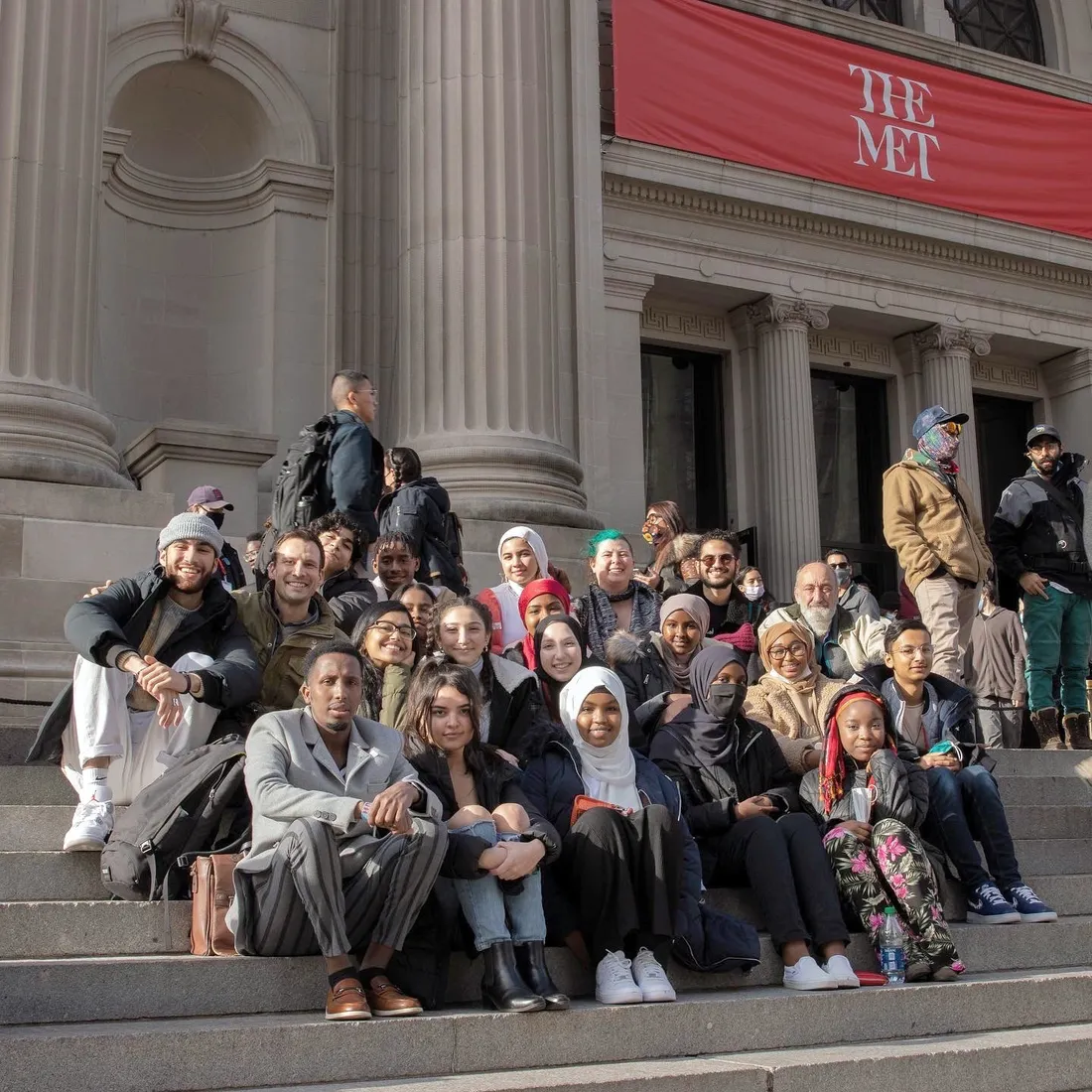 Group of students sitting on the steps outside the Metropolitan Museum of Art.