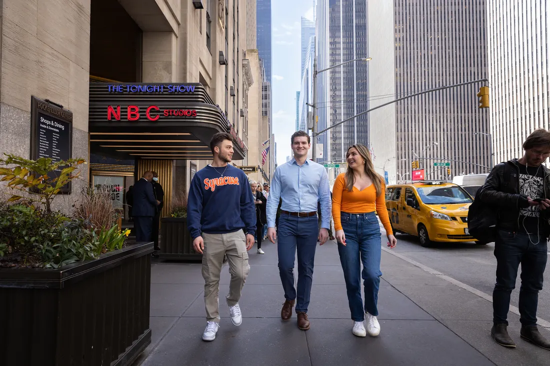Three people walking down the street in New York City.