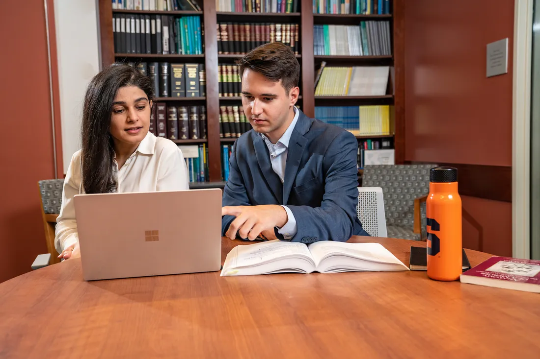 Management student and professor work together on a laptop