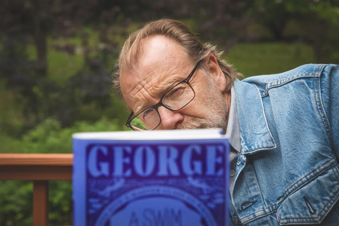 Portrait of George posed behind one of his books.