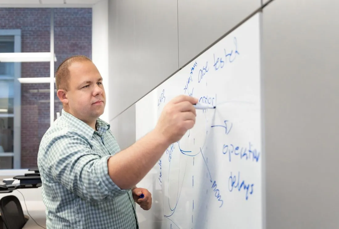 Professor writing on a white board. Click to read story.