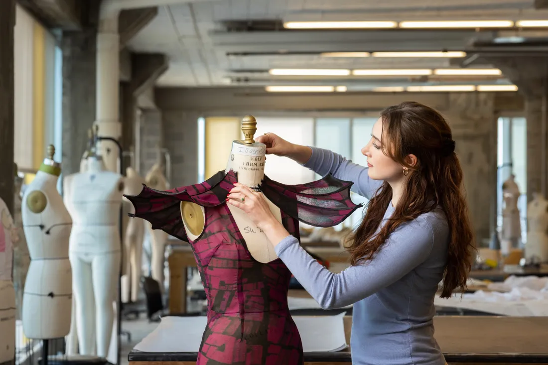 Isabelle Collins adjusting a dress on a mannequin.