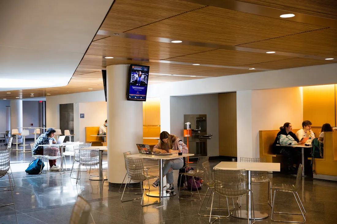 View of food court room with students studying at tables.
