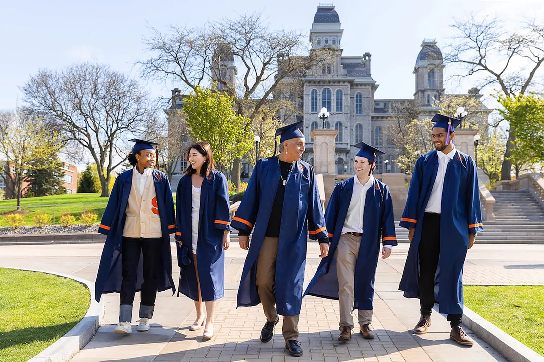 Students in caps and gowns walk together outside of the Hall of Languages.