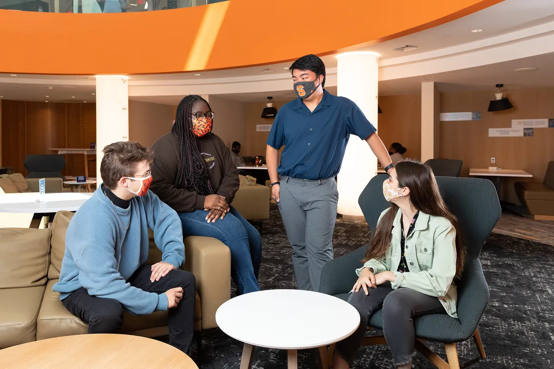 Group of students wearing masks have a conversation in Schine Student Center