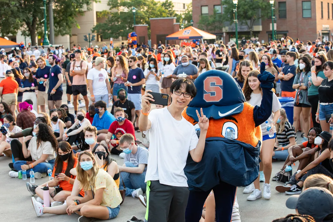 Student taking a selfie with Otto the Orange.