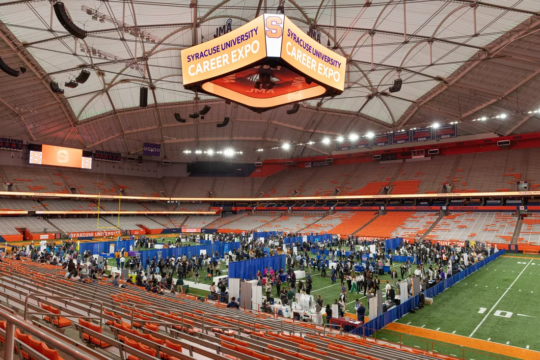 Wide shot of the inside of the JMA Wireless Dome. The football field filled with tables and people in conversation.