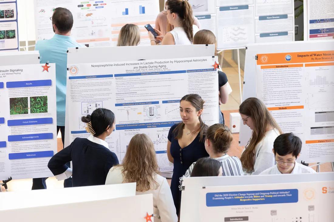 Students standing and smiling at a research symposium.