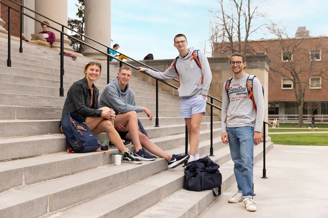 Four students sitting outside on steps.