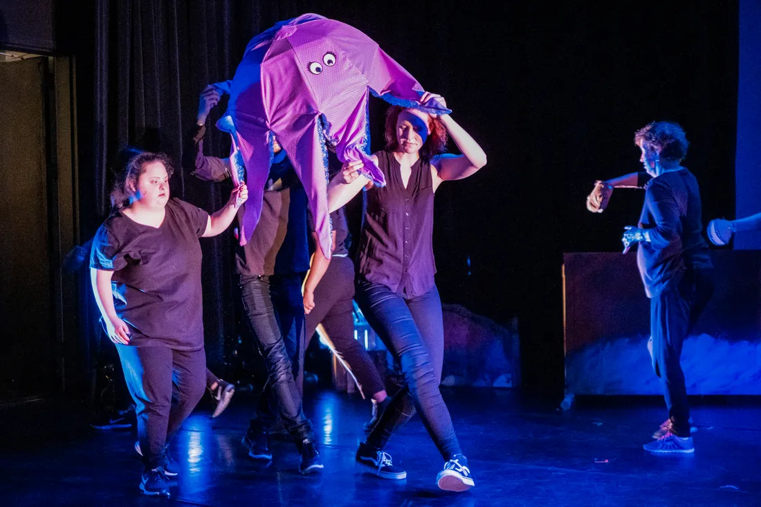 Laura Borgwardt and other performers on stage manipulating an octopus puppet above their heads.