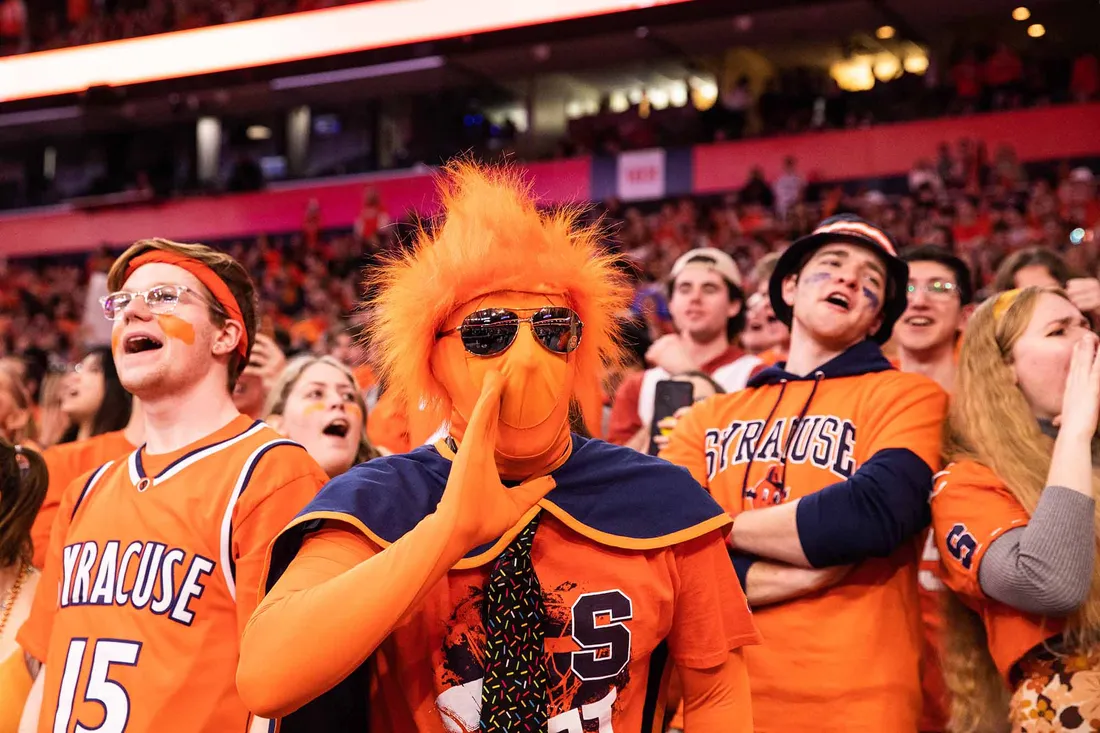 Student in full orange bodysuit cheers on the basketball team.