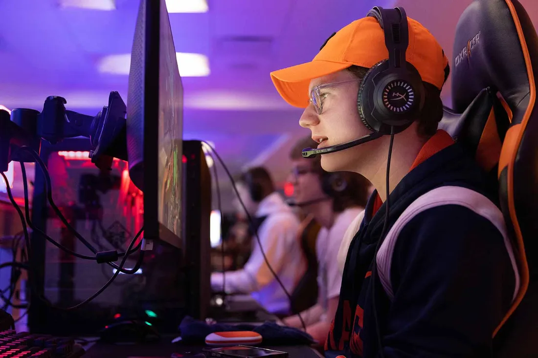 Braeden Cheverie-Leonard looks at his computer monitor while wearing a gaming headset in the esports.