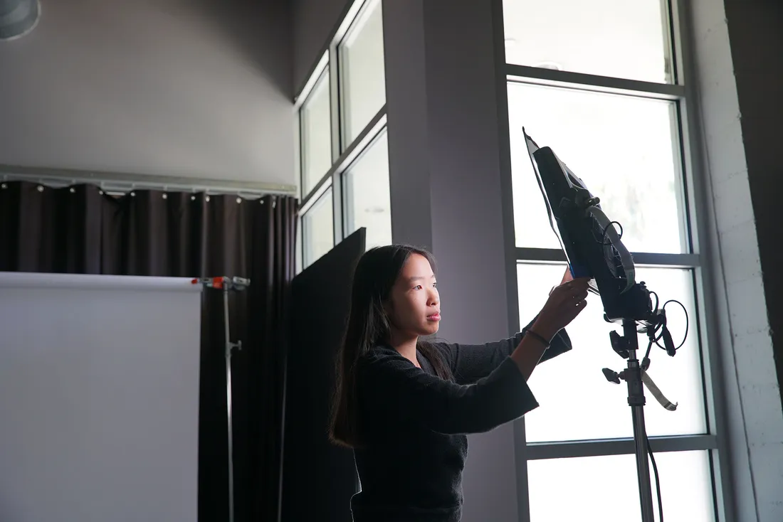 Maya Pow adjusts light in photography studio.