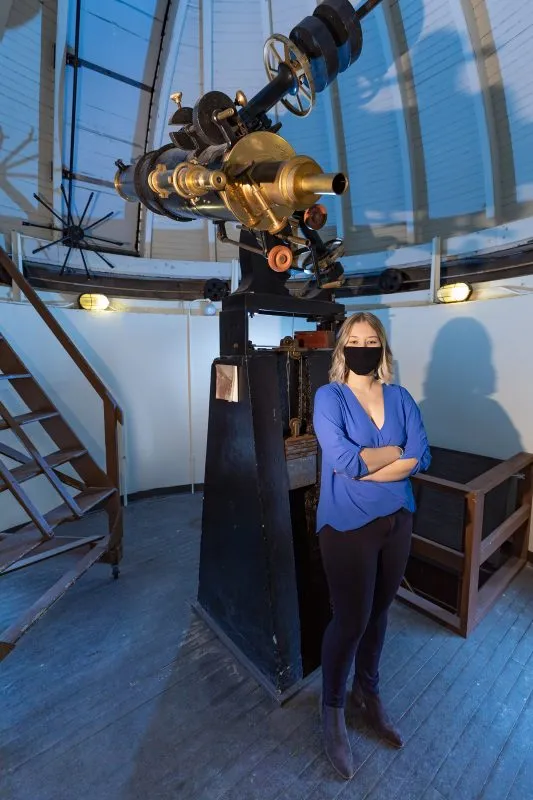 A student stands inside an observatory.