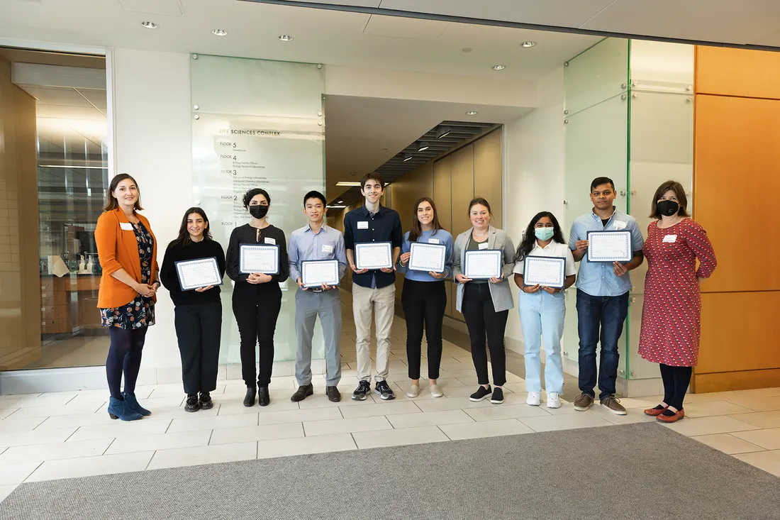 Individuals stand in row posing for photo holding certificates.