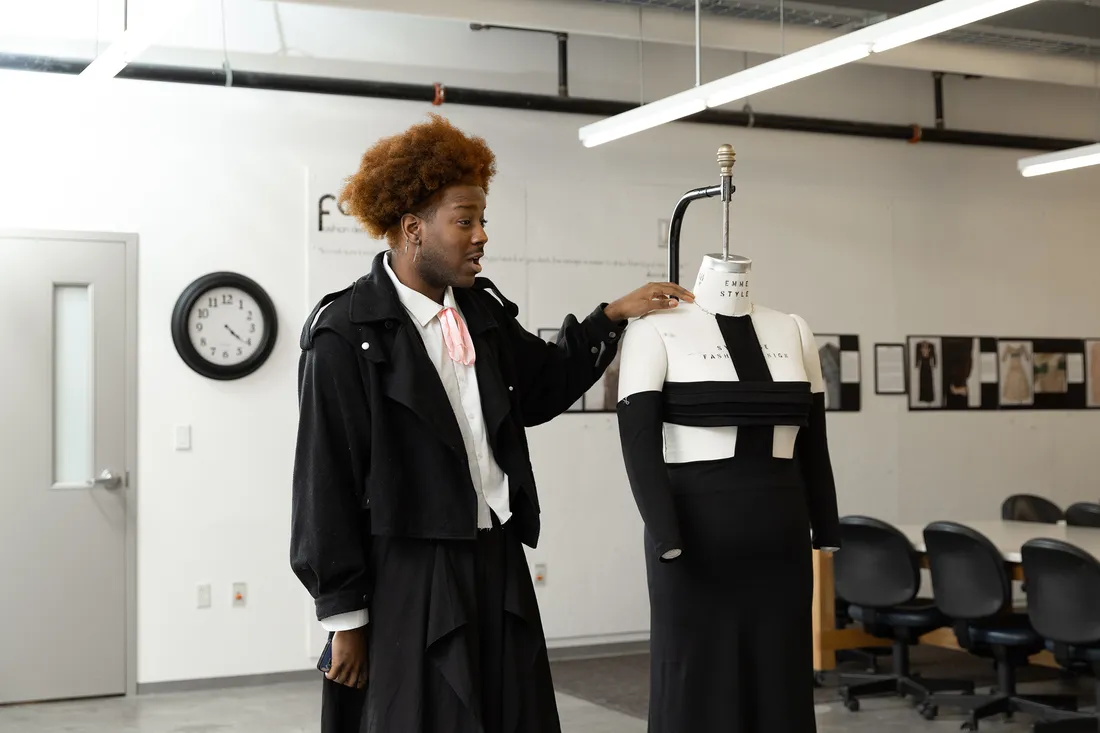 Photo of Williams standing next to a dress form with one of his designs on it.