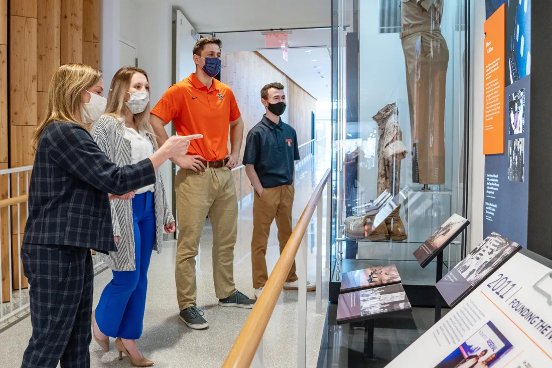 Four people looking at a display of military artifacts behind glass.