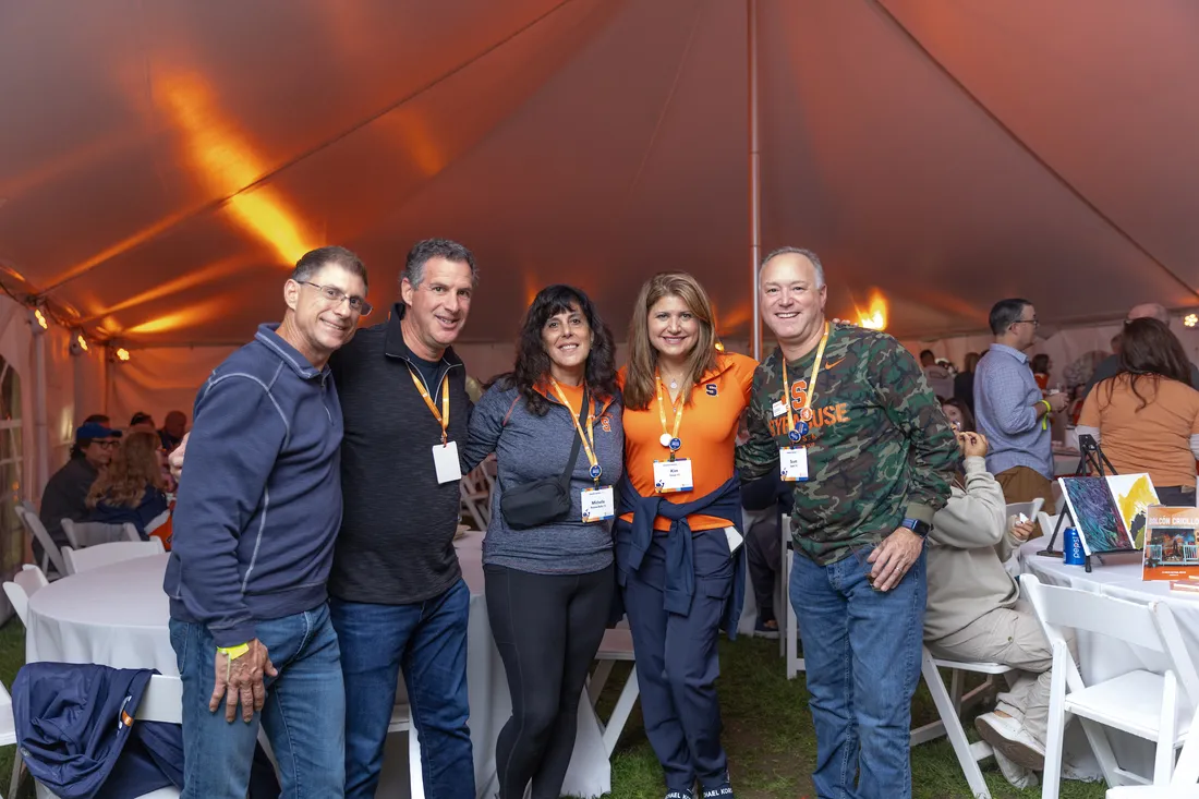 Alumni gather at Forever Orange event inside a tent.