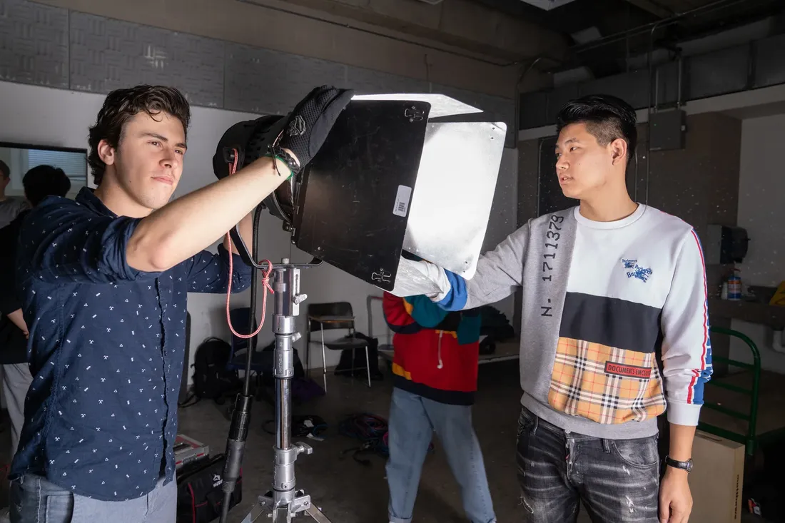 Students in cinematography lighting class adjusting light.