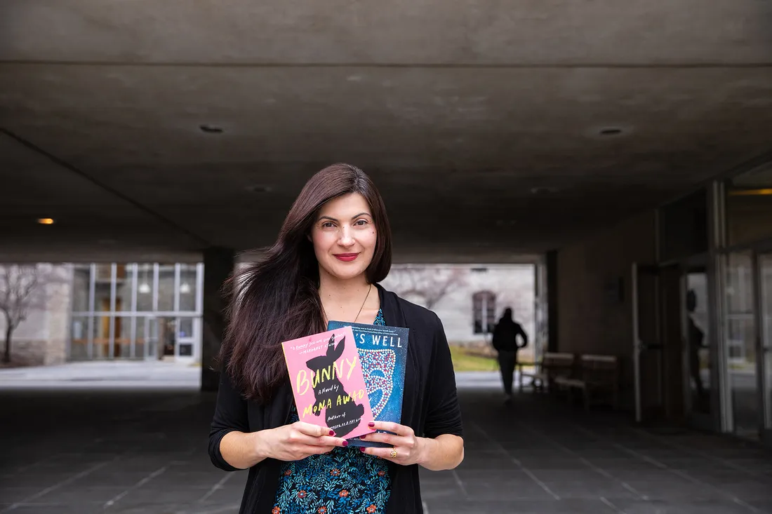 Portrait of Mona Awad holding her two novels, smiling.