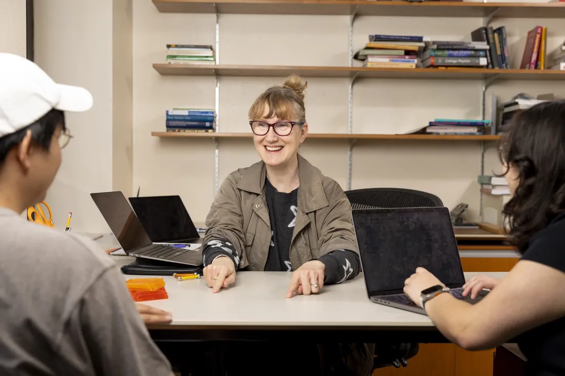 Professor at her desk talking to students.