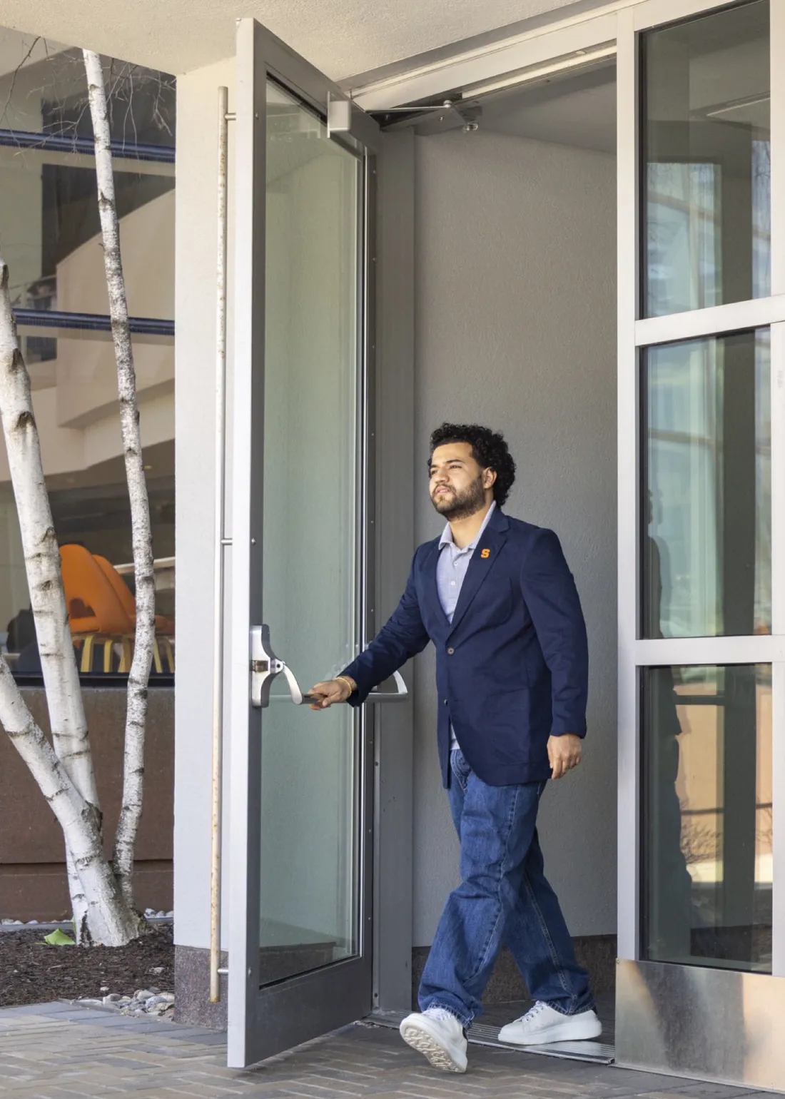 Thomas Castro-Chalarca '26 walking out the doors of the Martin J. Whitman School of Management.