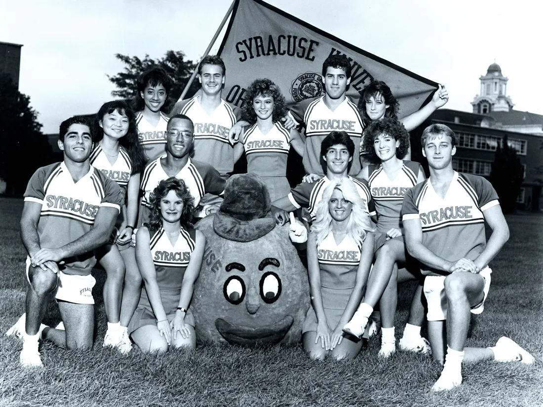Vintage Otto the orange mascot standing outside with cheerleaders.