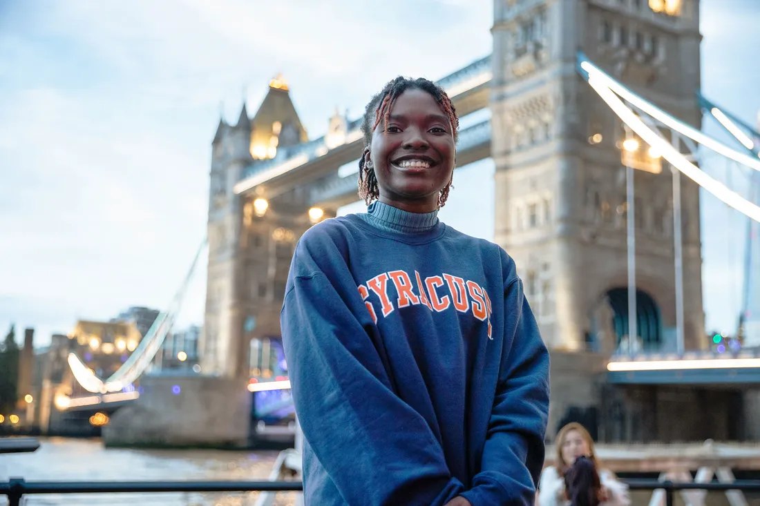 Person smiling in front of London Bridge.