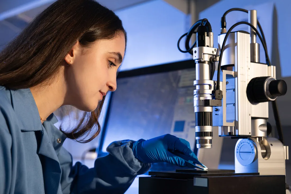Person working on microscope in a lab.