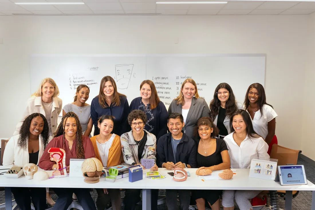 Faculty with students sitting at a table.