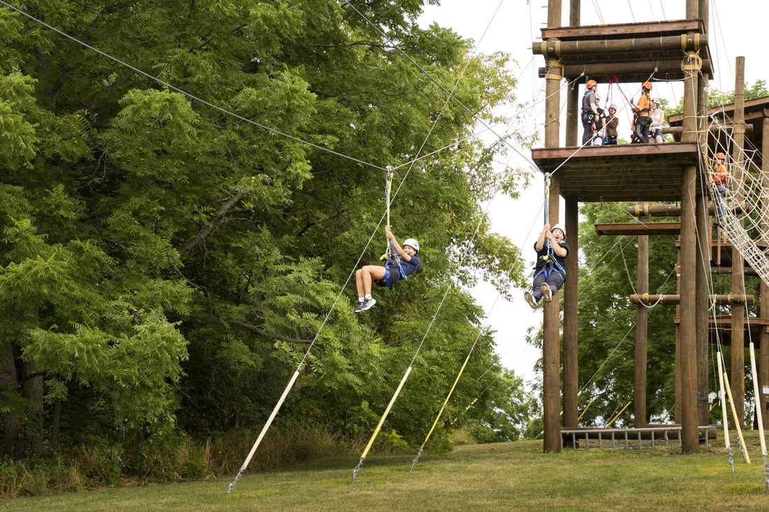 Students swinging down the ropes course and zip line on South Campus.