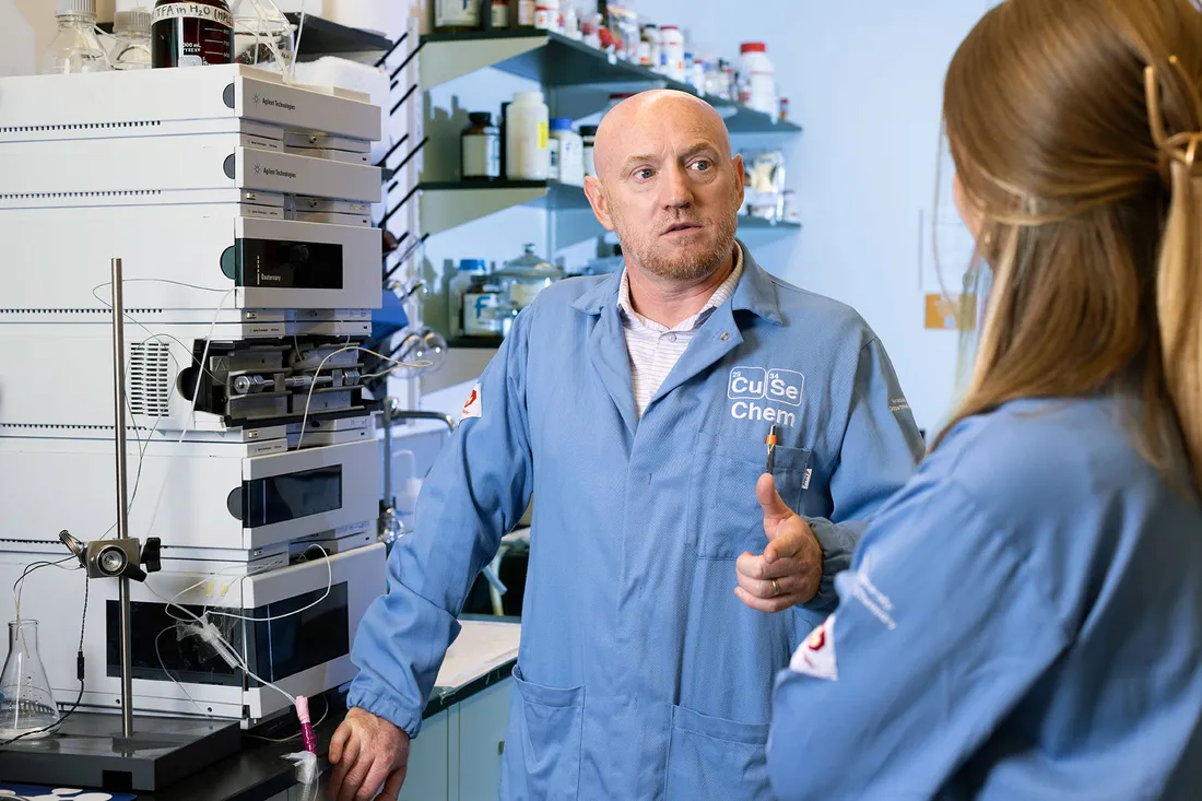 Professor and student talk beside equipment in lab.