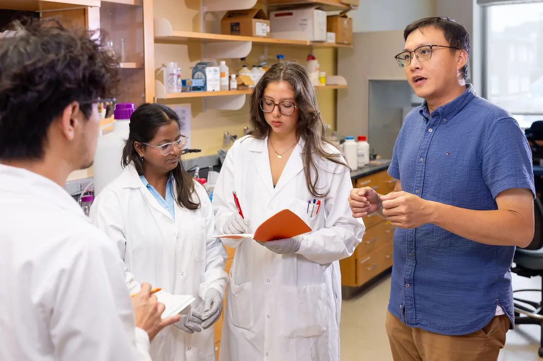 Students and professors talking in lab.