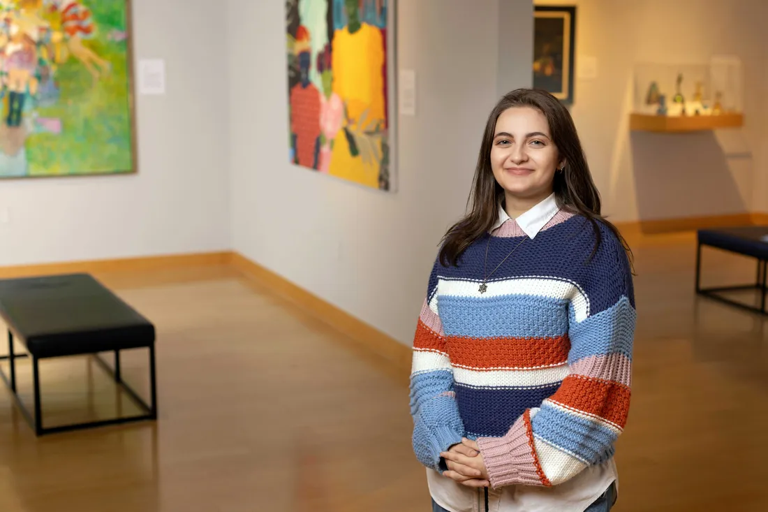 Annie Zusin standing and smiling in the Syracuse University art museum.