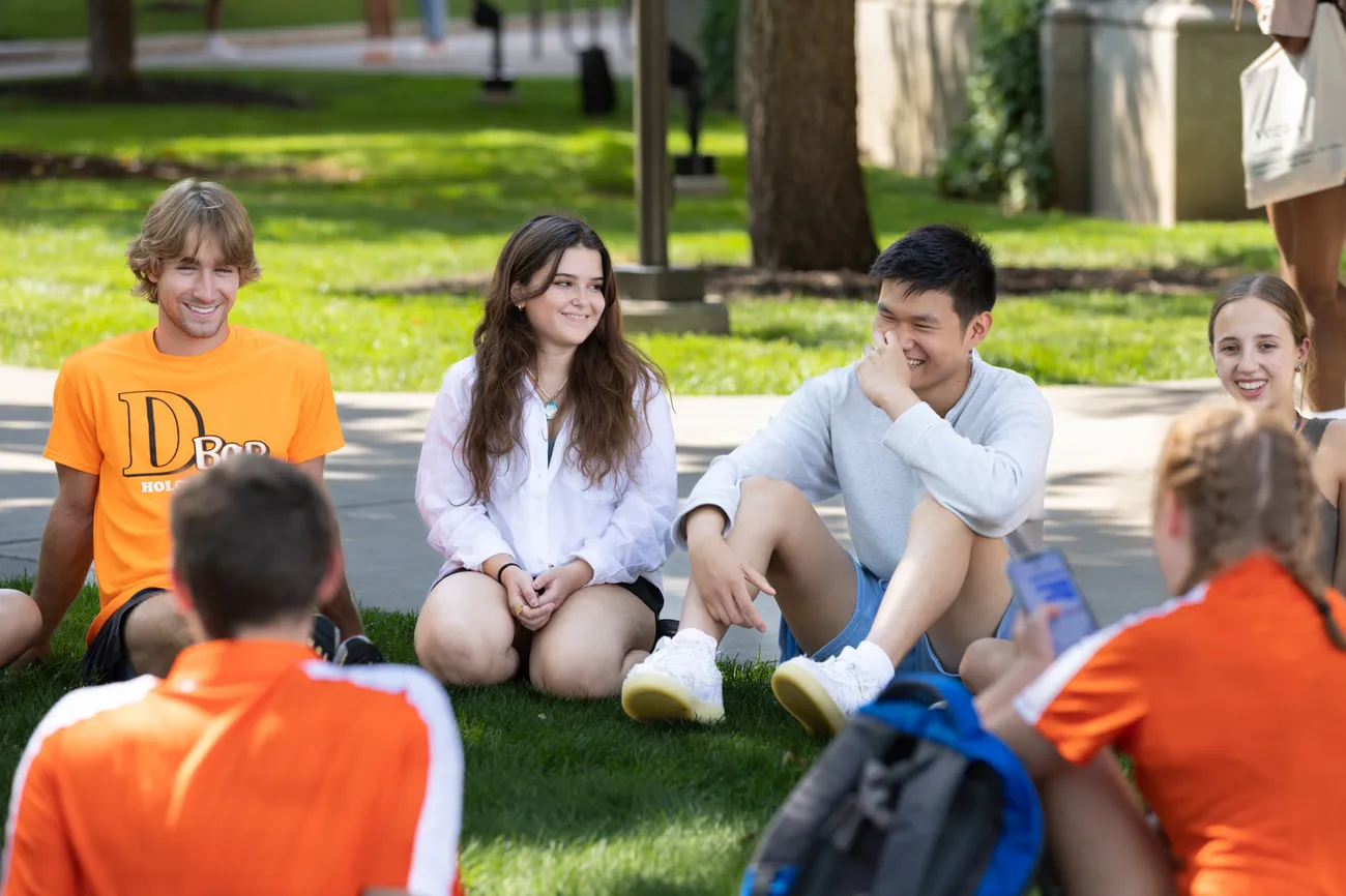 Students sitting and talking in a circle on the campus quad.