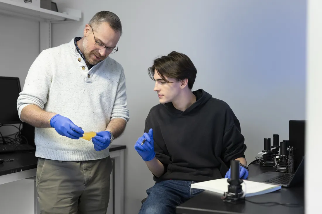 Two people in a lab looking at test tube vials.
