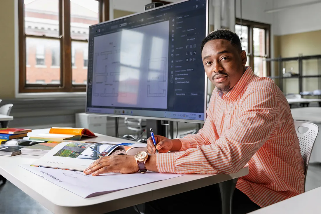 Student sits in front of screen with technical drawings on it.