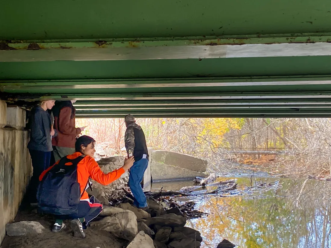 Four people standing under a bridge to examine it.