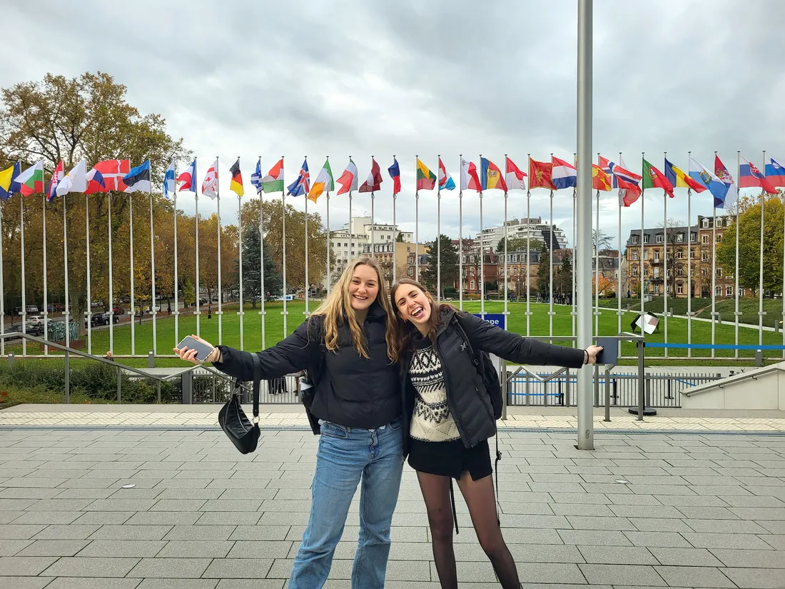 Students pose for picture in front of flags.