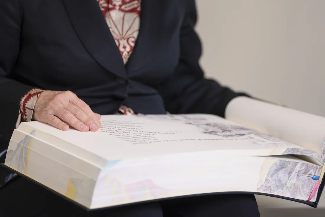 Close up of Diana Wege '76 reading a page from her book.