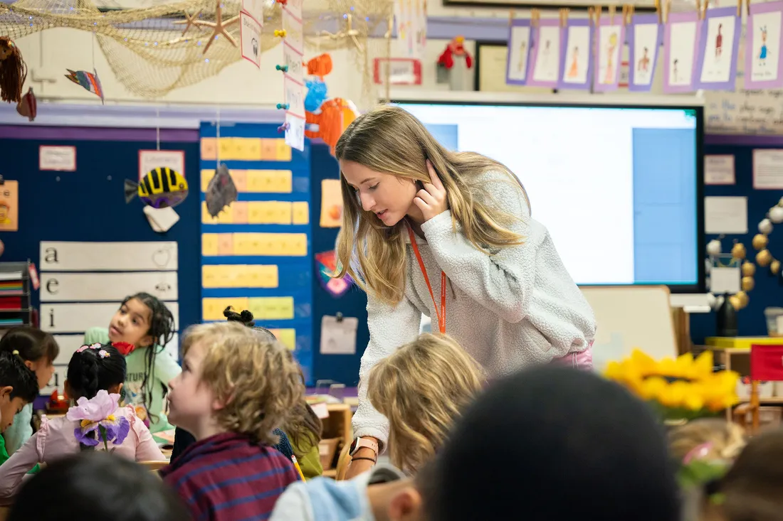 Student working in a classroom with children.