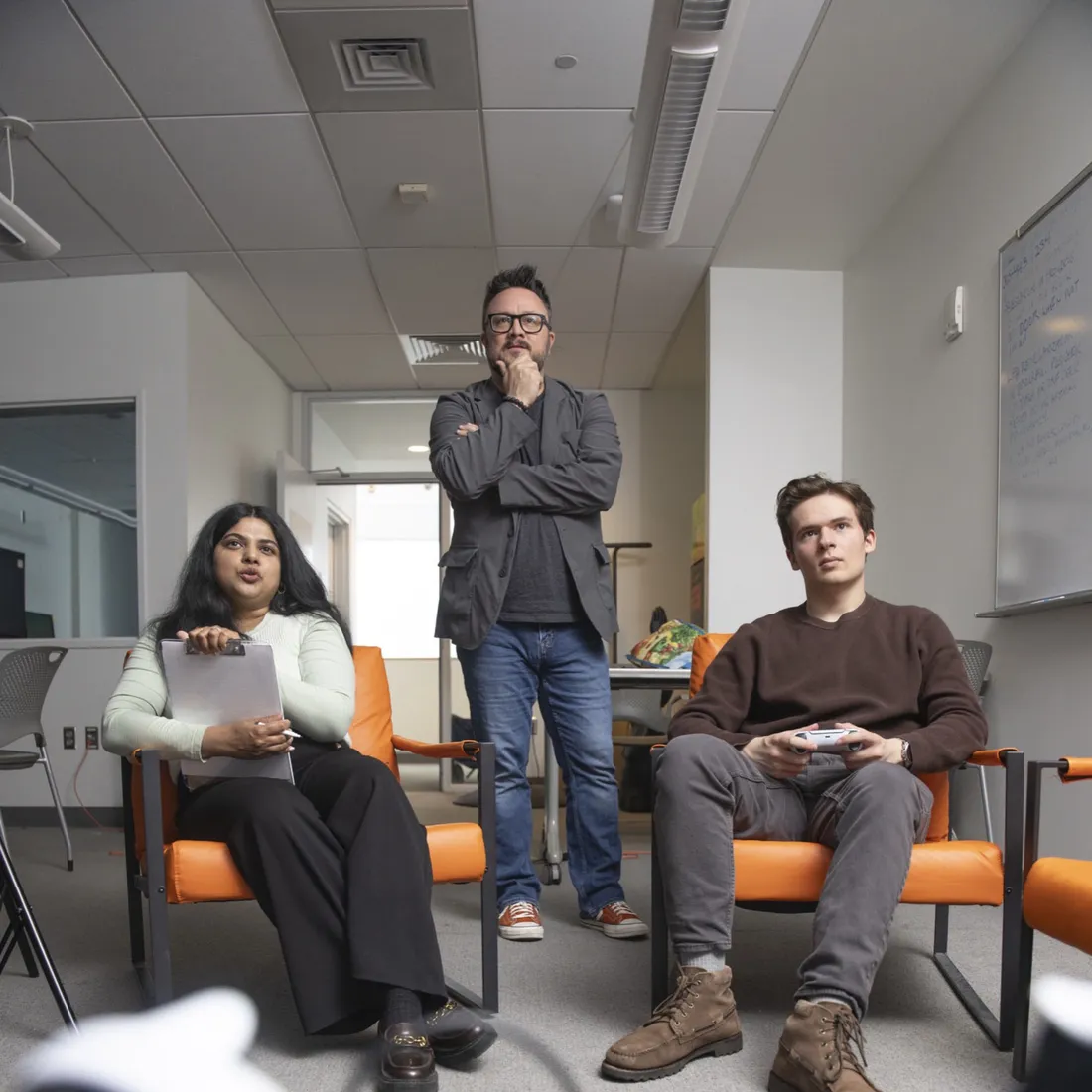 Professor Nick Bowman talking two students through playing a video game.