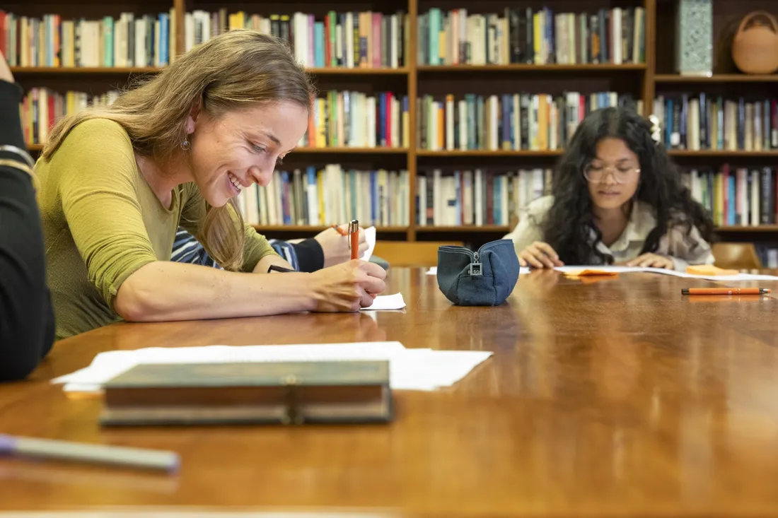 Two people sitting at a table taking notes.