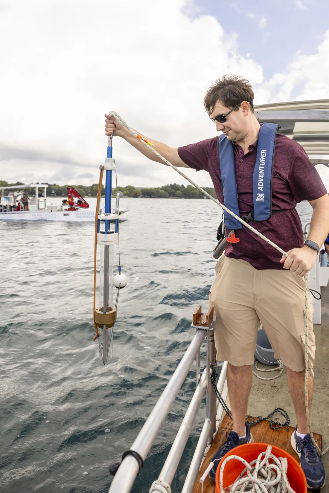 Postdoctoral student Nick Brennan holds a piece of sonar technology to submerge it in Skaneateles Lake for water quality research.