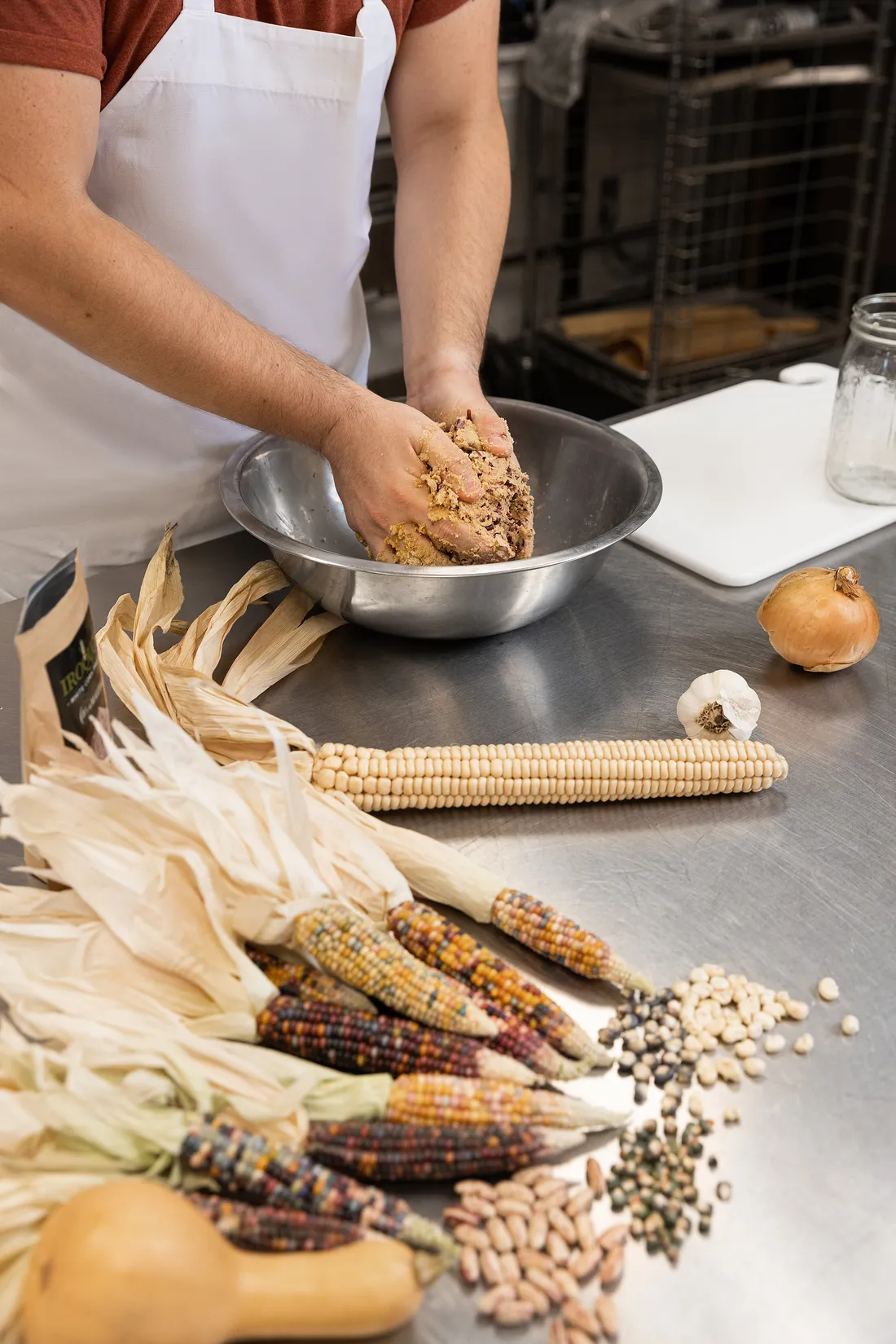 Close-up shot of a student mixing squash, corn and beans together in a bowl.