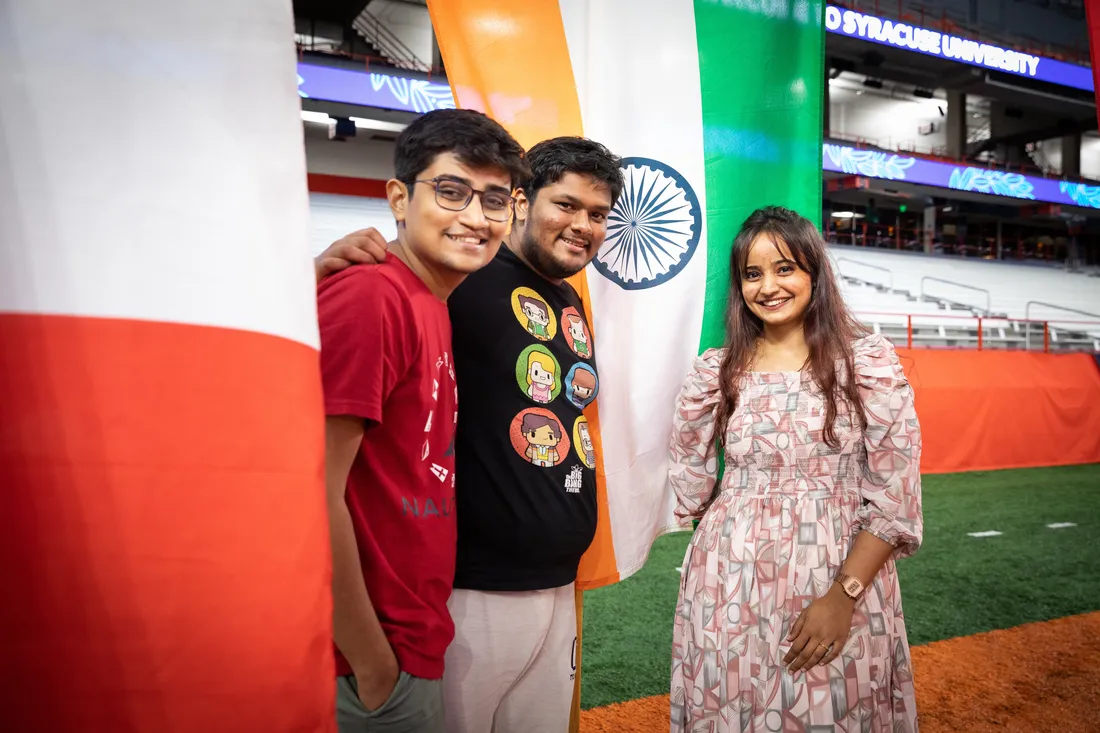 Three students stand in front of international flags.