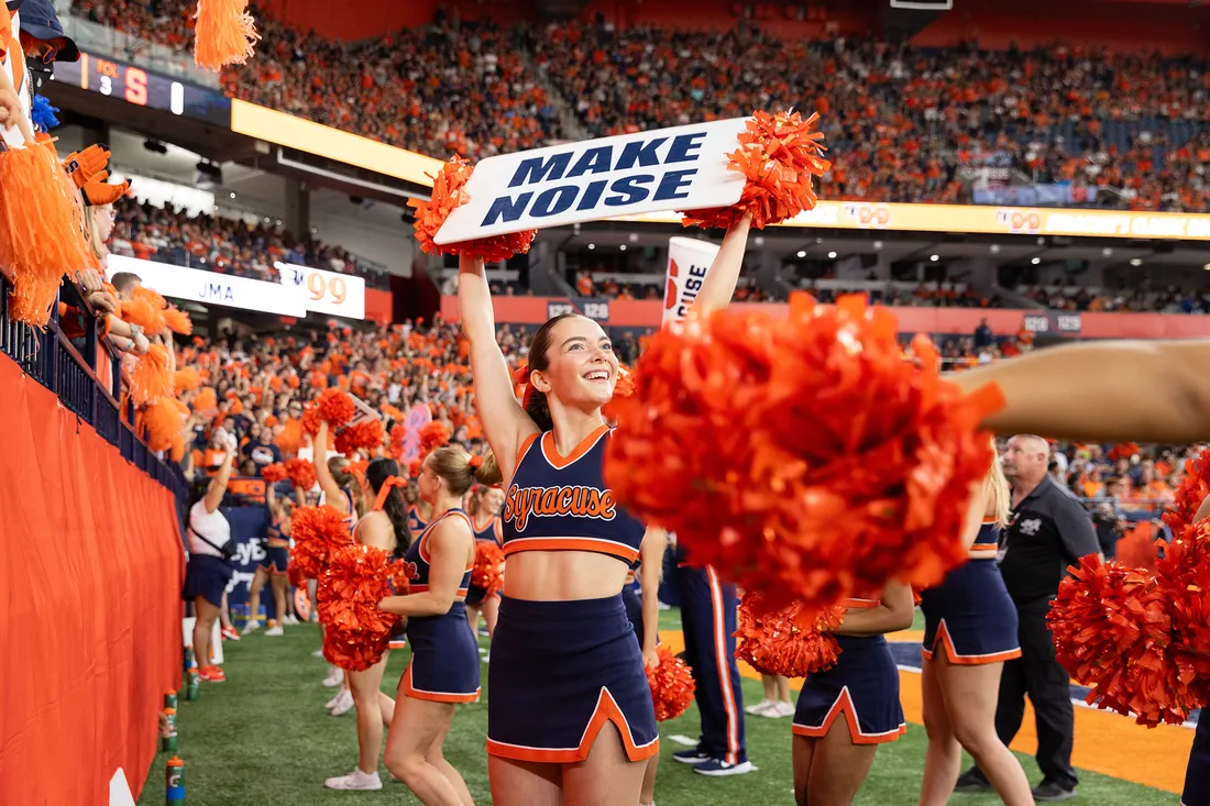 Cheerleader holding a sign hyping up the crowd.