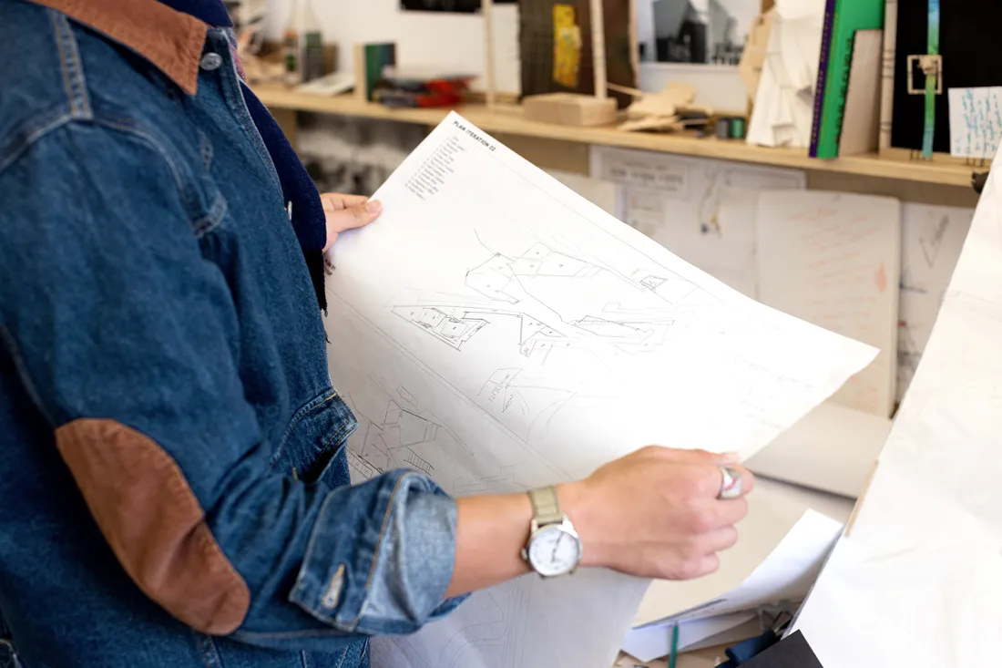 Closeup of Li holding his designs on a large piece of paper.