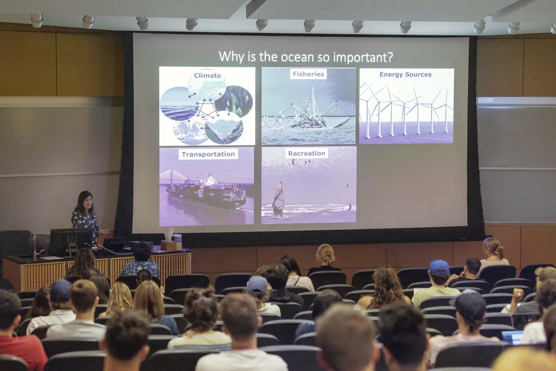Professor standing in front of classroom with presentation about ocean topics.